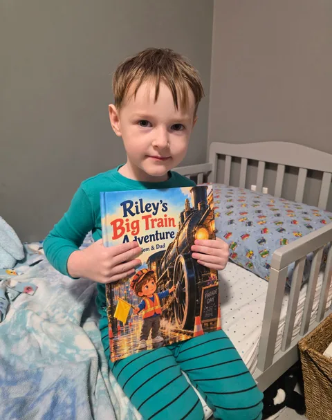 A child holding Riley’s Big Train Adventure on a bed
