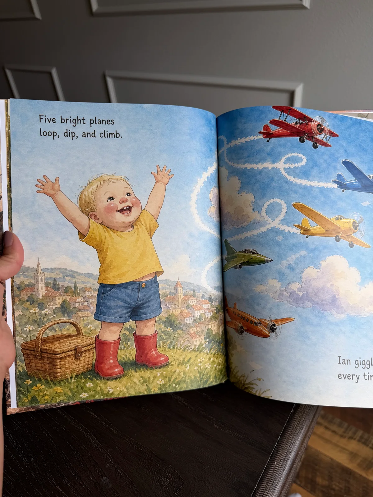 An open printed page from Ian’s counting book, with his illustrated character beside five planes