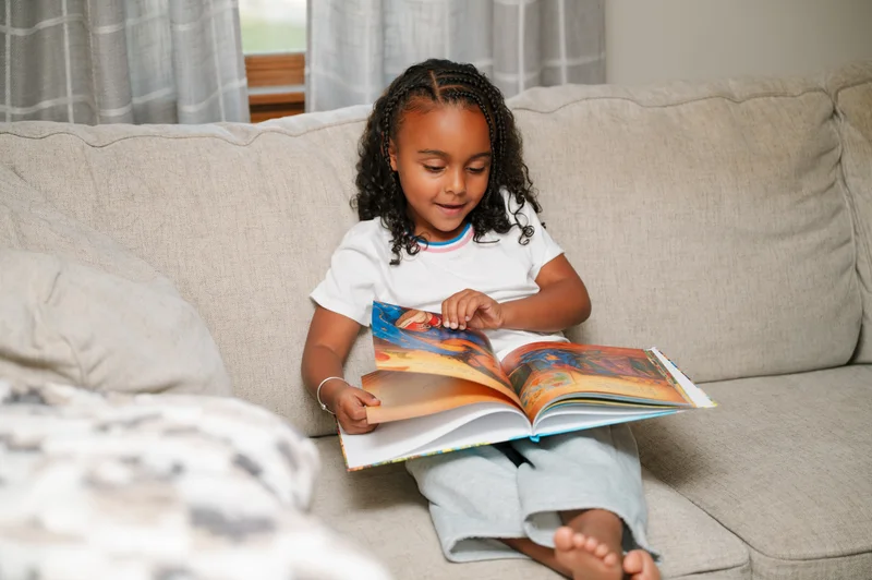 Reese reading her printed Sundayfawn storybook on a sofa