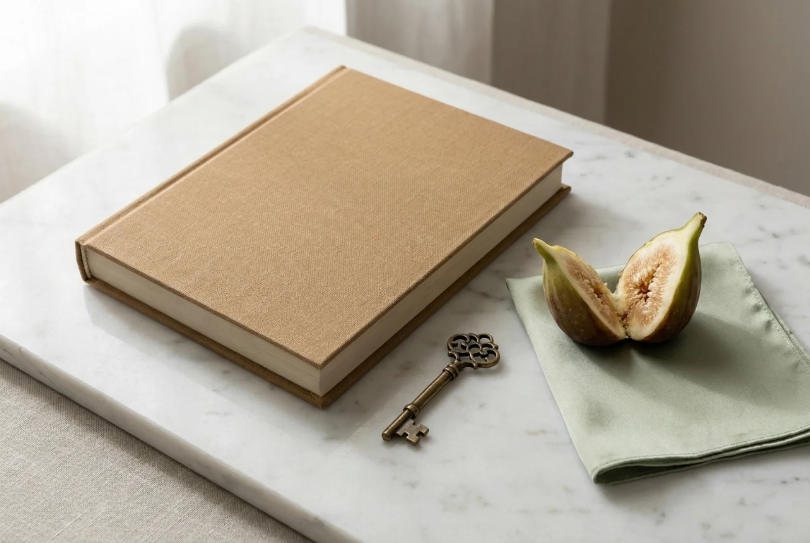 A small stack of cream and linen-bound hardcover picture books on a pale oak shelf beside a wooden figure and a porcelain mug, north-window light falling across the spines.