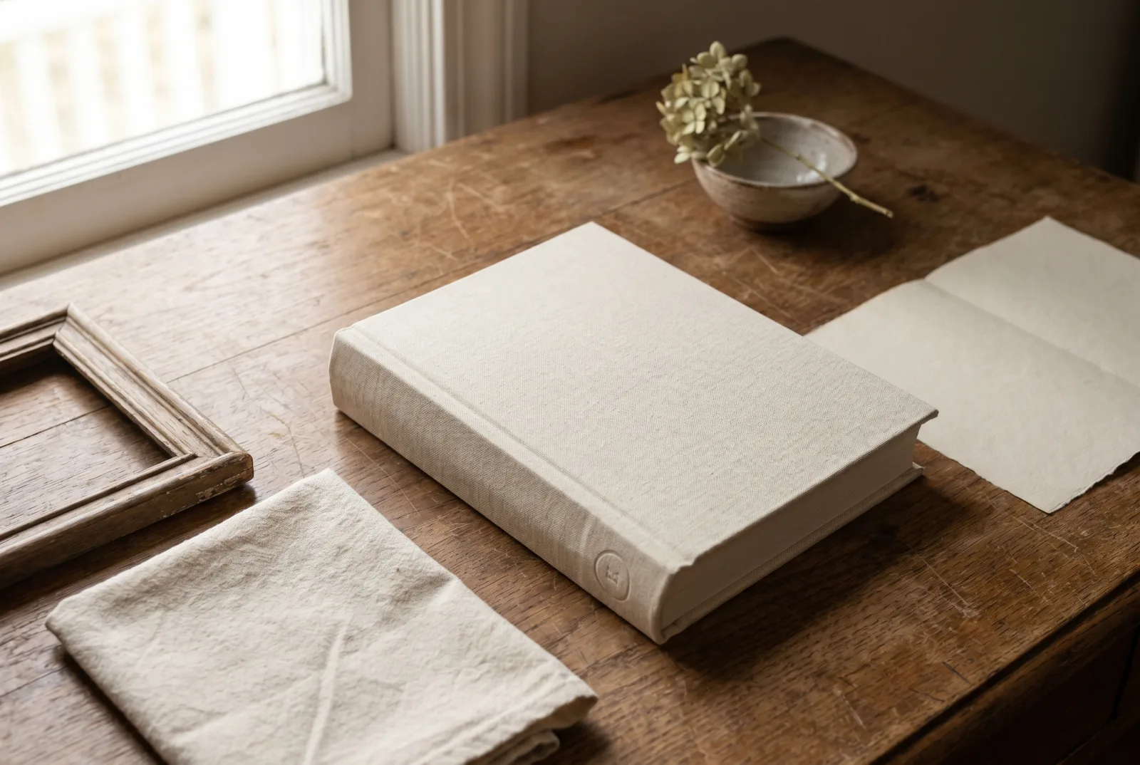 A stack of sundayfawn hardcover storybooks on a cream table — an adventure book open to a watercolour spread, an ABC volume beside it, a milestone-birthday book.