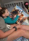 Riley and his parent looking at the train illustrations inside his book.
